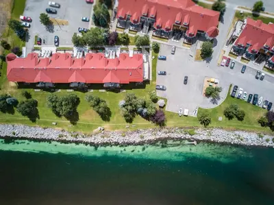 an aerial view of a building with red roofs next to the water at Riverside by StayIn in Fernie