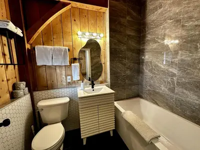a bathroom with a toilet and a sink and a tub at Waterfront Timber-Frame Cottage! in Ucluelet
