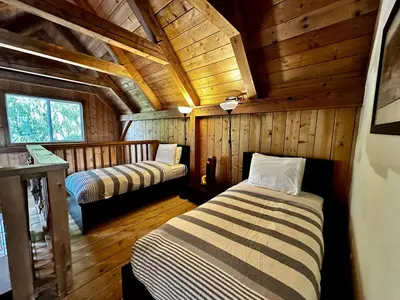 a bedroom with two beds in a wooden cabin at Waterfront Timber-Frame Cottage! in Ucluelet