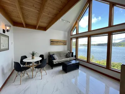 a living room with a couch and a table and chairs at Private Oceanfront Cabin With Hot Tub Doc Holiday Cabin in Ucluelet