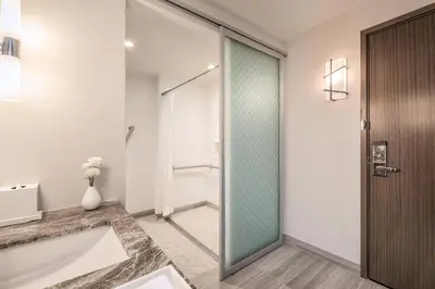 a bathroom with a tub and a glass shower door at Civic Hotel, Autograph Collection in Surrey