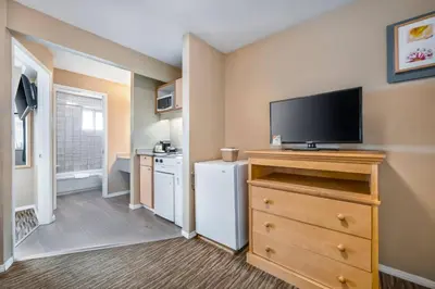 a room with a flat screen tv on a dresser with a kitchen at Econo Lodge Inn & Suites in North Vancouver