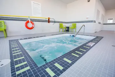a large swimming pool with green chairs in a room at Holiday Inn Hotel & Suites Calgary South - Conference Ctr by IHG in Calgary