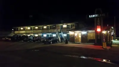 a building with cars parked in a parking lot at night at RANCHLAND Inn in Nanton