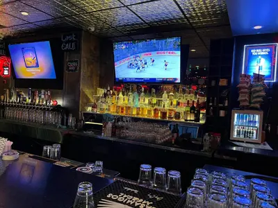 a bar with a television and a counter with alcohol at Commercial Hotel in Edmonton