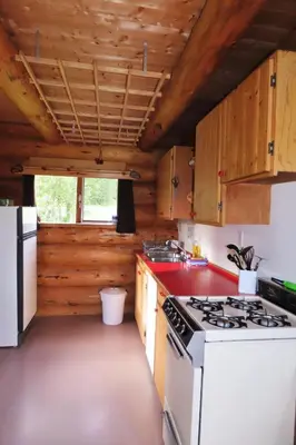 a kitchen with wooden cabinets and a stove top oven at Rocky Ridge Resort-BC in Smithers