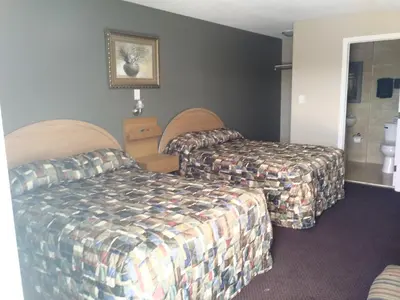 a hotel room with two beds and a bathroom at Aries Motel in Edson