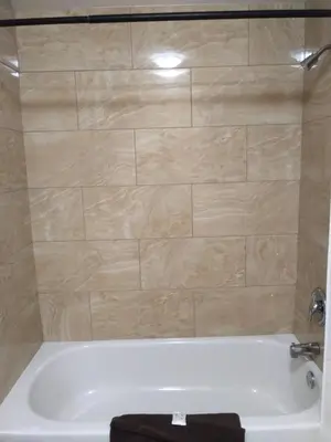 a bathroom with a tub with a tiled shower at Aries Motel in Edson