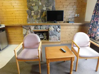 two chairs and a table in a living room with a fireplace at Timberland Hotel in Hinton