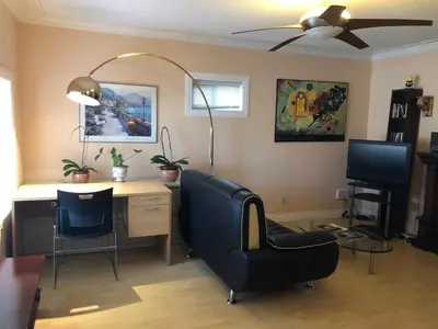 a living room with a desk and a chair and a fan at Cozy Bedrooms Guest House in Vancouver