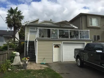 a large house with a garage and a truck at Cozy Bedrooms Guest House in Vancouver