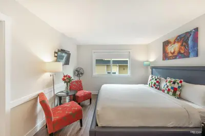 a bedroom with a bed and a chair and a window at Queens Hotel in New Westminster