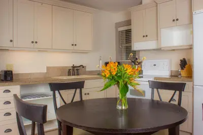 a kitchen with a table with a vase of flowers on it at The Cottages on Salt Spring Island in Ganges