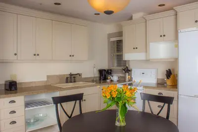 a kitchen with a table with a vase of flowers on it at The Cottages on Salt Spring Island in Ganges
