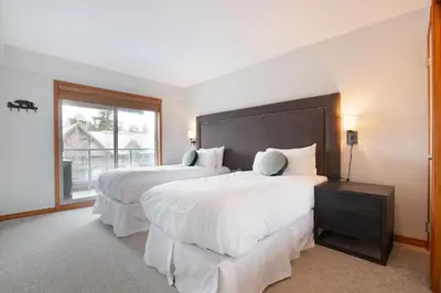 a bedroom with two beds and a large window at Aspens Mountain Side Resort in Whistler