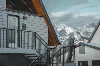 a man standing on the stairs of a building with a mountain at Basecamp Resorts Canmore in Canmore