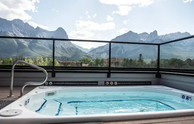 a jacuzzi tub with a view of mountains at Basecamp Resorts Canmore in Canmore