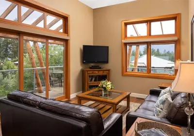 a living room with a couch and a tv and windows at Outback Lakeside Vacation Homes in Vernon