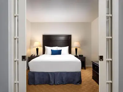 a bedroom with a large white bed with blue pillows at Huntingdon Hotel and Suites in Victoria