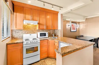 a kitchen with wooden cabinets and a white stove top oven at Best Western PLUS Inner Harbour Hotel in Victoria