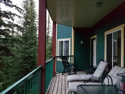 a porch with chairs and tables on a house at Vacation Homes by The Bulldog- Berker's Suite A in Silver Star