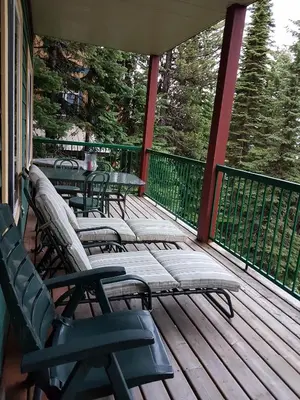 a deck with chairs and tables on a porch at Vacation Homes by The Bulldog- Berker's Suite A in Silver Star
