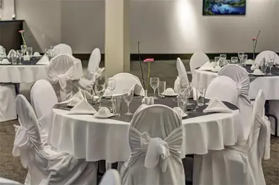 a group of tables with white chairs in a room at Sea to Sky Hotel and Conference Centre in Squamish