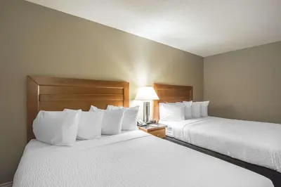 two beds in a hotel room with white pillows at Quality Inn West Edmonton in Edmonton