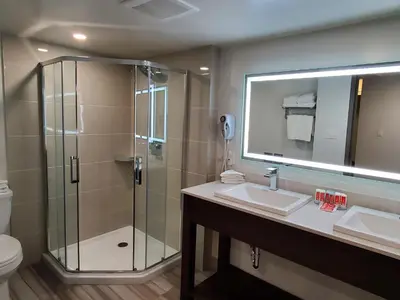 a bathroom with a shower and a sink and a mirror at Super 8 by Wyndham Macleod Trail Calgary in Calgary