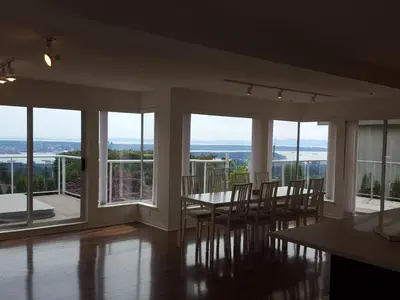 a dining room with a table and chairs and windows at Emperial Suites in North Vancouver