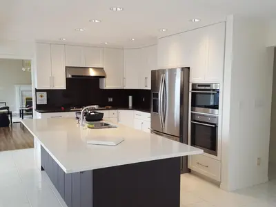 a kitchen with white cabinets and a stainless steel refrigerator at Emperial Suites in North Vancouver