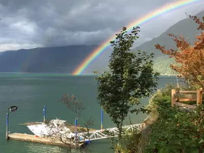 a rainbow over a body of water with a boat at The Lodge on Harrison Lake in Harrison Hot Springs