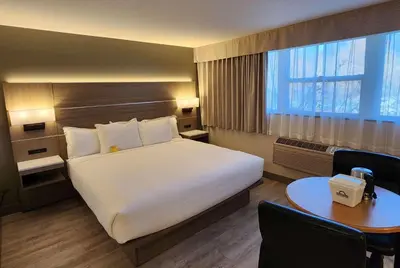 a hotel room with a large bed and a table at Days Inn by Wyndham Penticton Conference Centre in Penticton