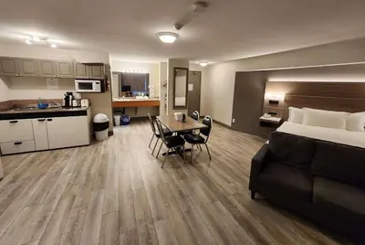 a hotel room with a bed and a table and a kitchen at Days Inn by Wyndham Penticton Conference Centre in Penticton