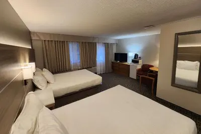 a hotel room with two beds and a mirror at Days Inn by Wyndham Penticton Conference Centre in Penticton