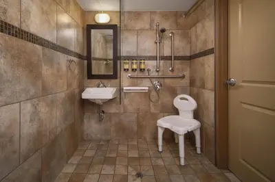 a bathroom with a toilet and a sink and a chair at Best Western Plus Kamloops Hotel in Kamloops