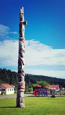a totem pole in a park with a playground at Sea Raven Motel in Queen Charlotte