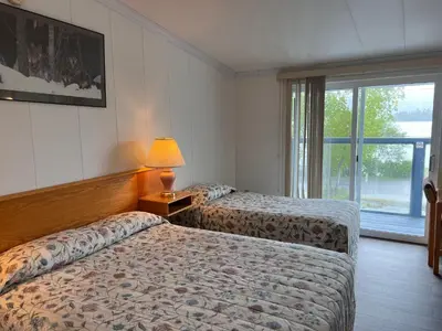 two beds in a hotel room with a window at Sea Raven Motel in Queen Charlotte