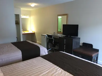 a hotel room with two beds and a desk and a television at Bear Country Inn in Terrace