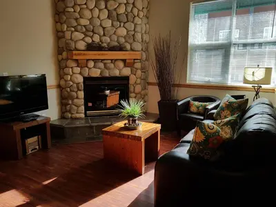 a living room with a couch and a stone fireplace at Sunset Resorts Canmore and Spa in Canmore
