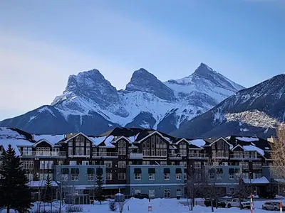 a building with snow covered mountains in the background at Sunset Mountain Inn in Canmore