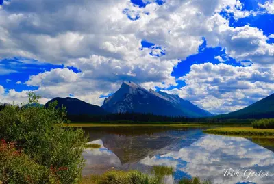 a mountain reflection in a lake with a cloudy sky at Sunset Mountain Inn in Canmore