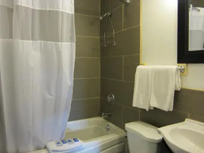 a bathroom with a white shower curtain and a toilet and a sink at Trans Canada Motel in Kamloops
