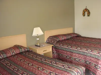 a hotel room with two beds and a table with a lamp at Trans Canada Motel in Kamloops
