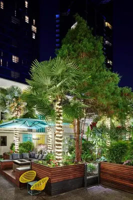 a garden with palm trees and chairs and a building at The Burrard in Vancouver