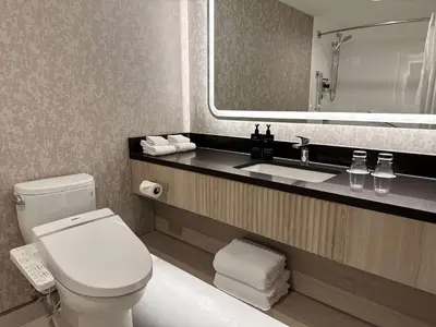 a bathroom with a toilet and a sink and a mirror at Coast Victoria Hotel & Marina by APA in Victoria