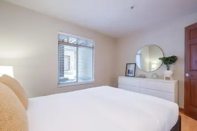 a white bedroom with a bed and a mirror at Lagoons by Outpost Whistler in Whistler