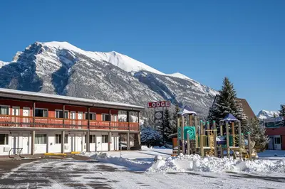 a hotel with a playground in front of a mountain at Rocky Mountain Ski Lodge in Canmore