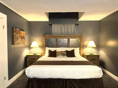a bedroom with a large bed with two nightstands and two lamps at Divya Sutra Plaza and Conference Centre, Vernon, BC in Vernon