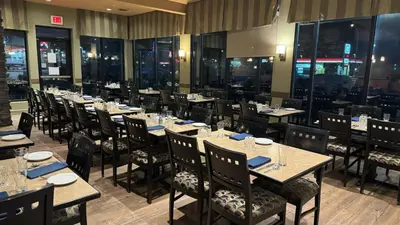 a dining room with tables and chairs and windows at Divya Sutra Plaza and Conference Centre, Vernon, BC in Vernon